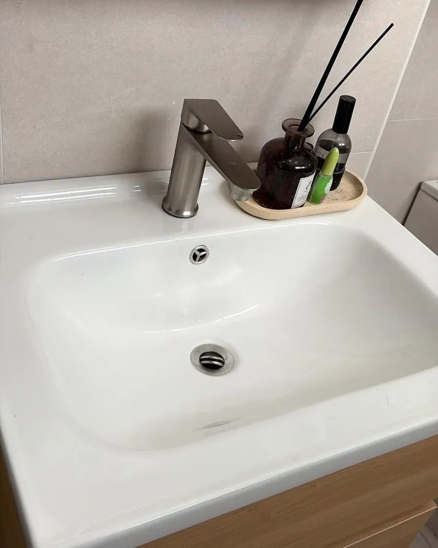 New brushed basin mixer tap installed on a white basin above a timber vanity in Singapore