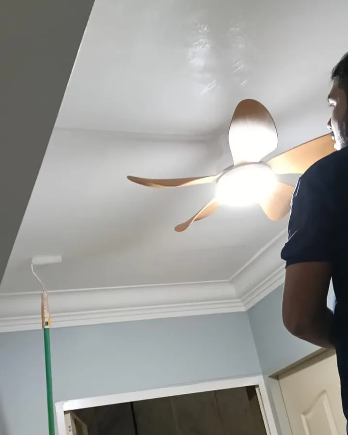 Installed wooden-blade ceiling fan with its light switched on in a Singapore living room