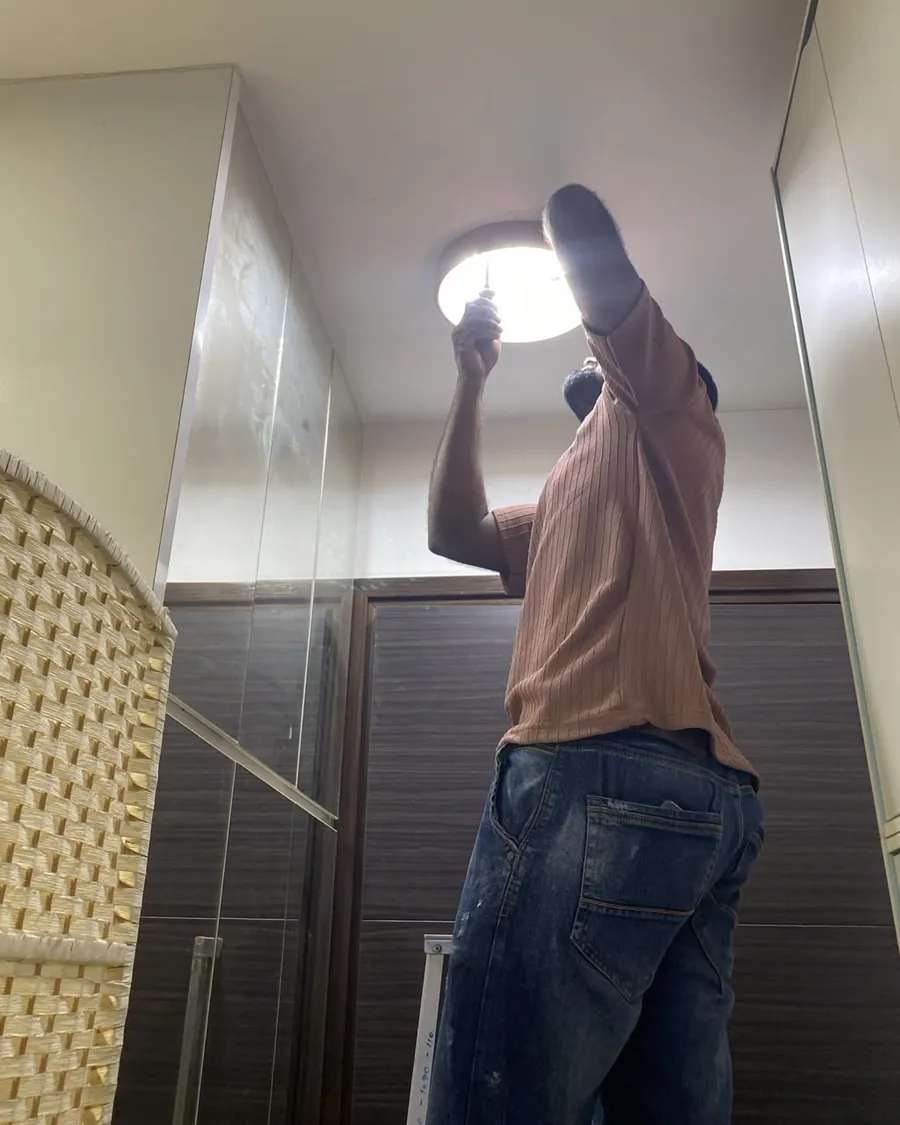 Technician replacing a ceiling light fitting in a walk-in wardrobe in a Singapore condo