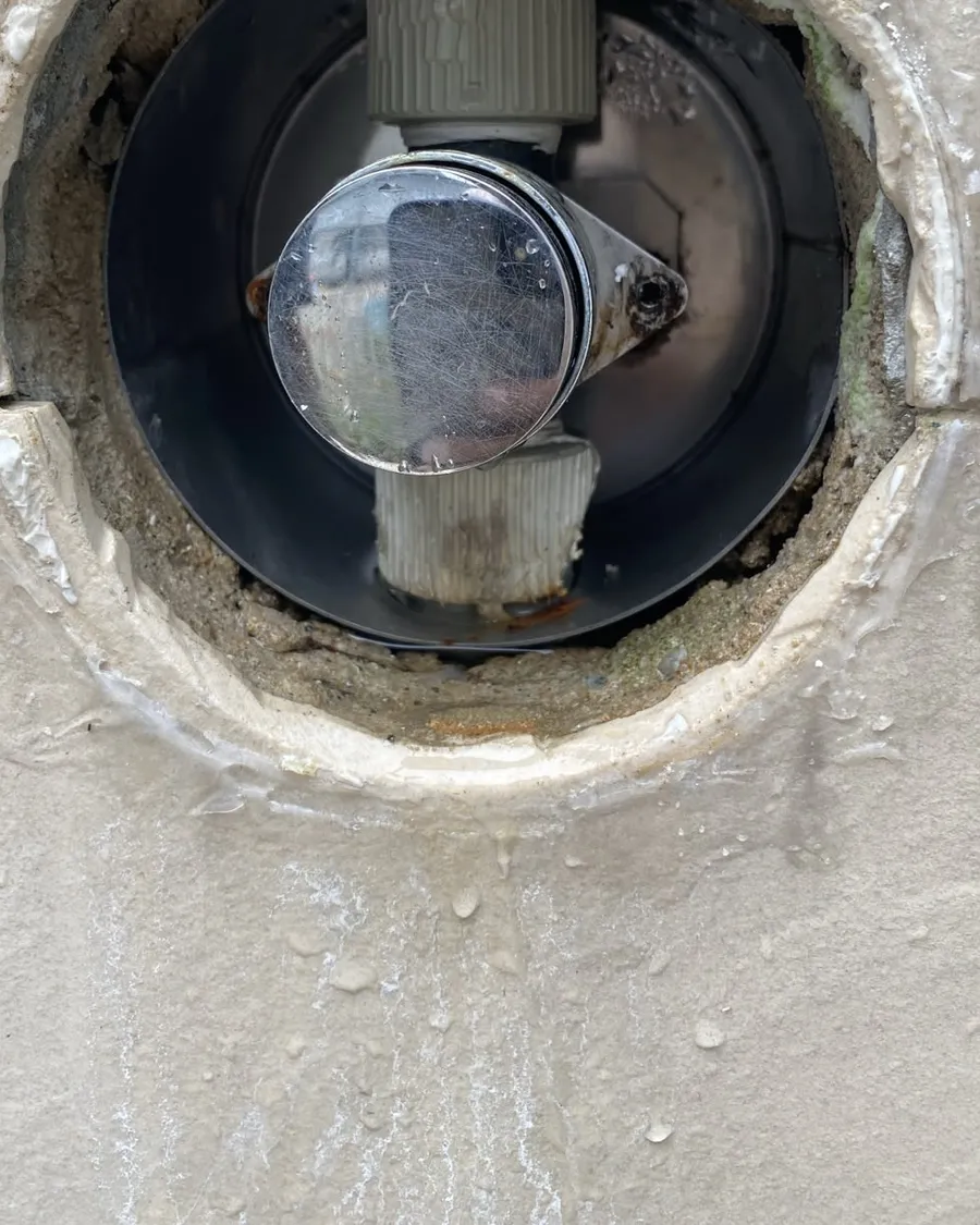 Concealed shower mixer valve body inside a circular opening hacked into a tiled wall in Singapore