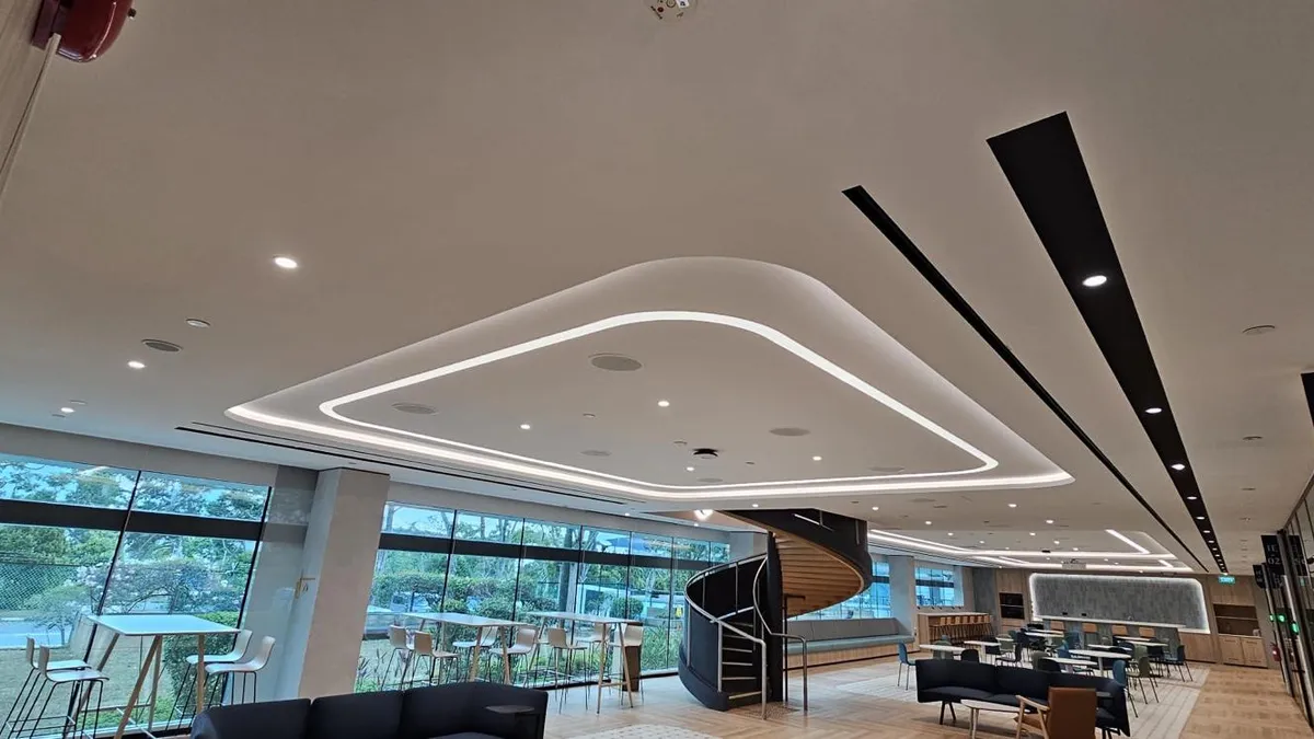 Shaped false ceiling with LED cove lighting above a café seating area in Singapore