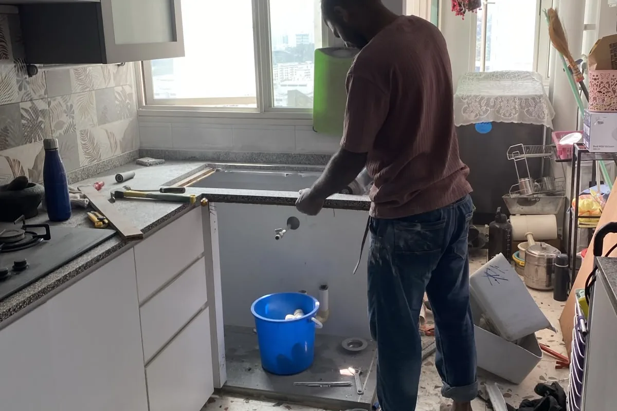 Technician working at a kitchen worktop cut-out during a sink replacement in a Singapore flat