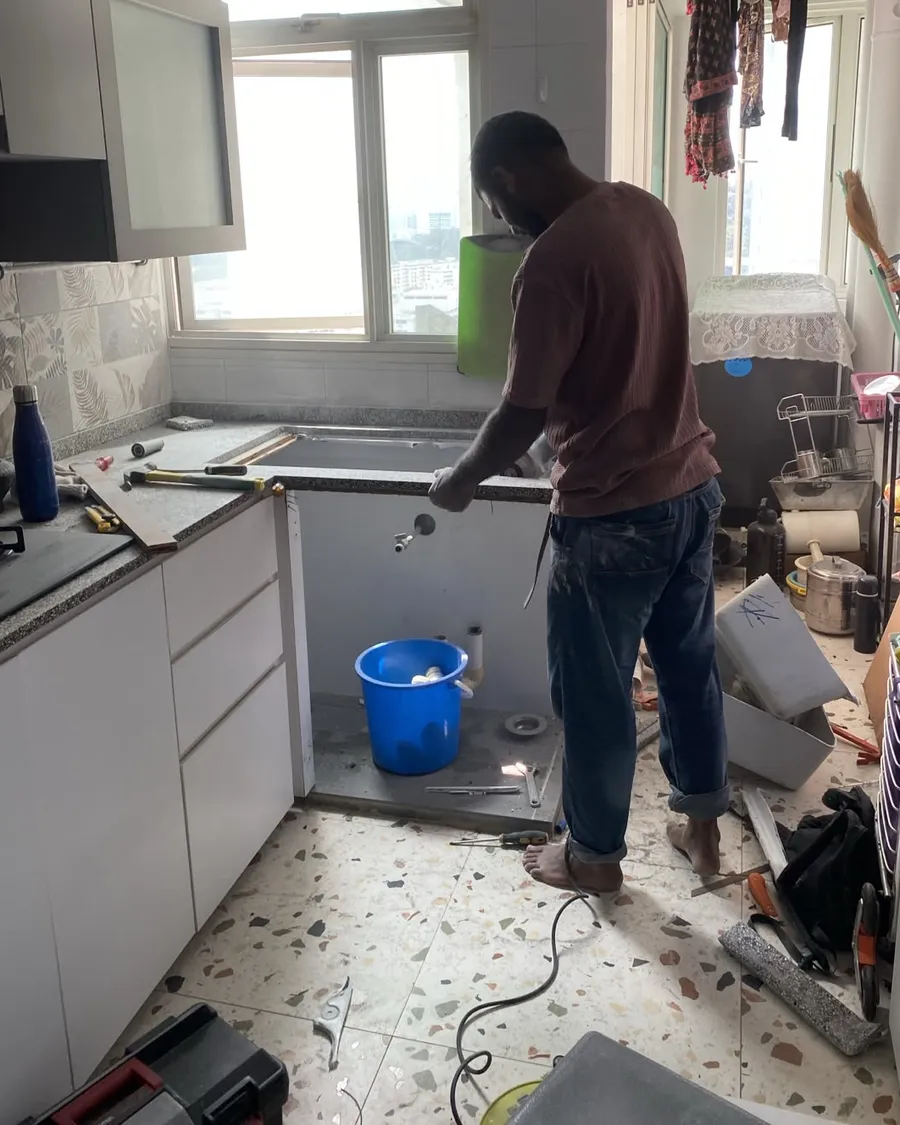 Technician working at a kitchen worktop cut-out during a sink replacement in a Singapore flat