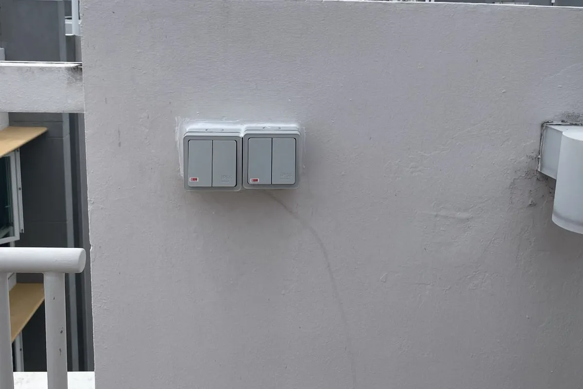 Weatherproof switches and a wall light installed on a rooftop terrace wall in Singapore