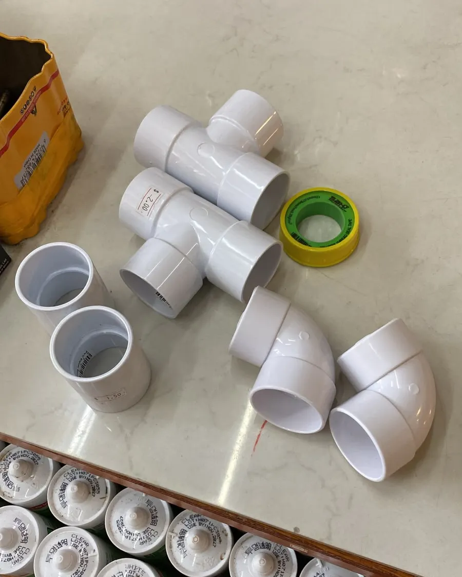 PVC waste pipe fittings and thread tape laid out on a worktop before a plumbing job in Singapore