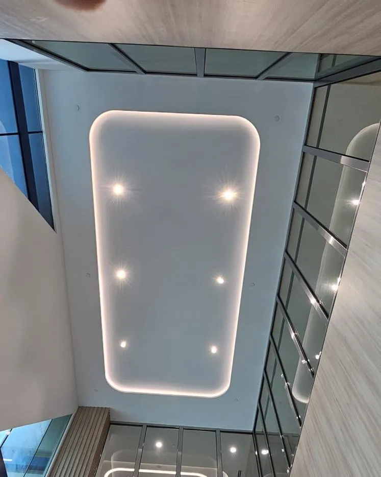 Recessed cove-lit ceiling panel with downlights in a double-height atrium in Singapore