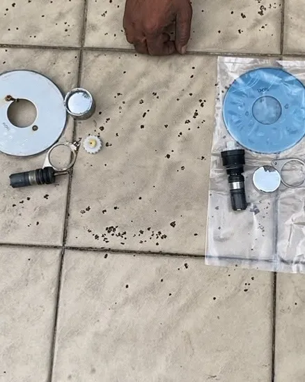 Shower valve cartridge, plate and fixings laid out on tiles before installation in Singapore