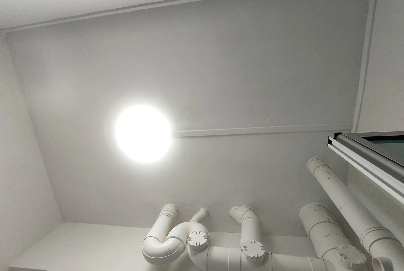 Freshly repainted toilet ceiling with exposed pipework in a Singapore HDB bathroom